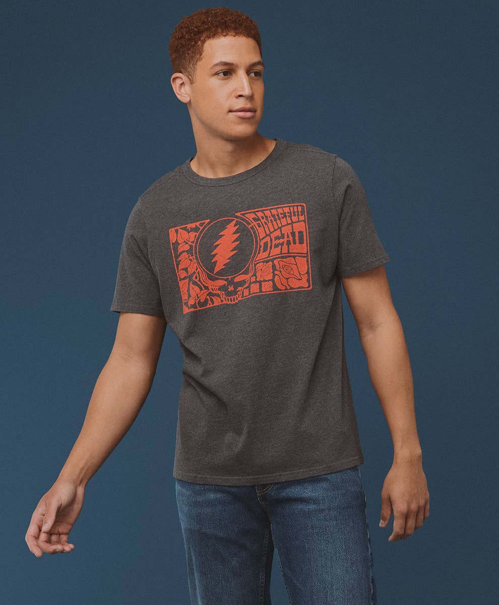 Man wearing a dark gray t-shirt with an orange graphic design on a blue background
