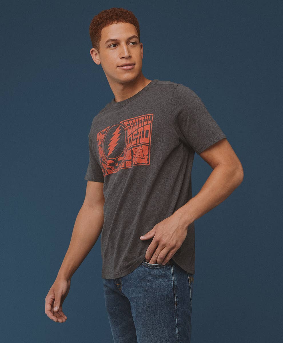 Man wearing Greatful Dead dark gray t-shirt with a red graphic design on a blue background