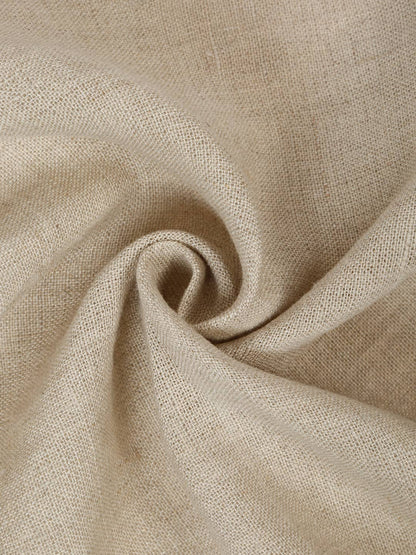A close-up of a light beige linen fabric napkins with a soft, textured weave, artistically draped in a spiral pattern.