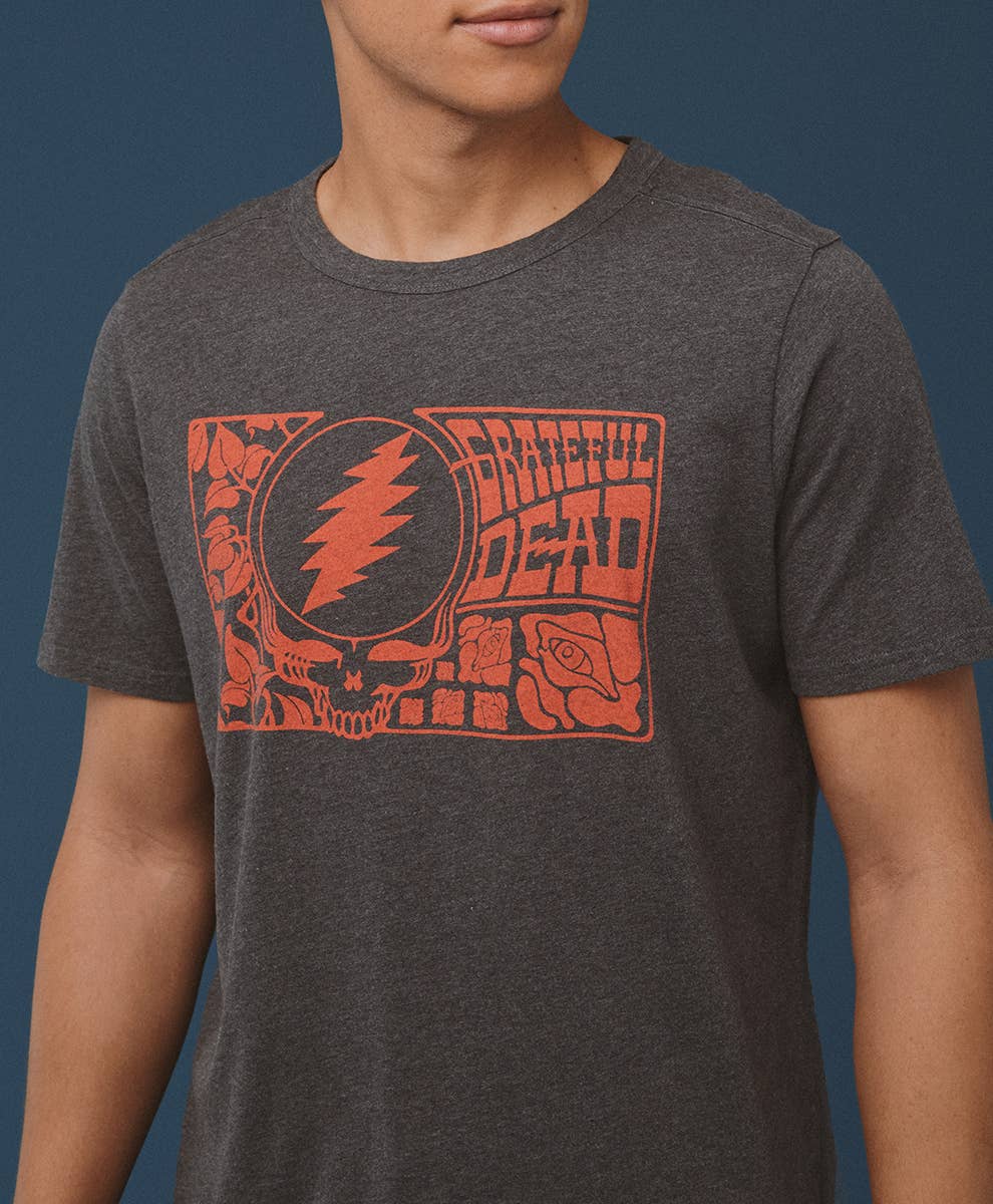 Person wearing a dark gray t-shirt with a red Grateful Dead logo on a blue background