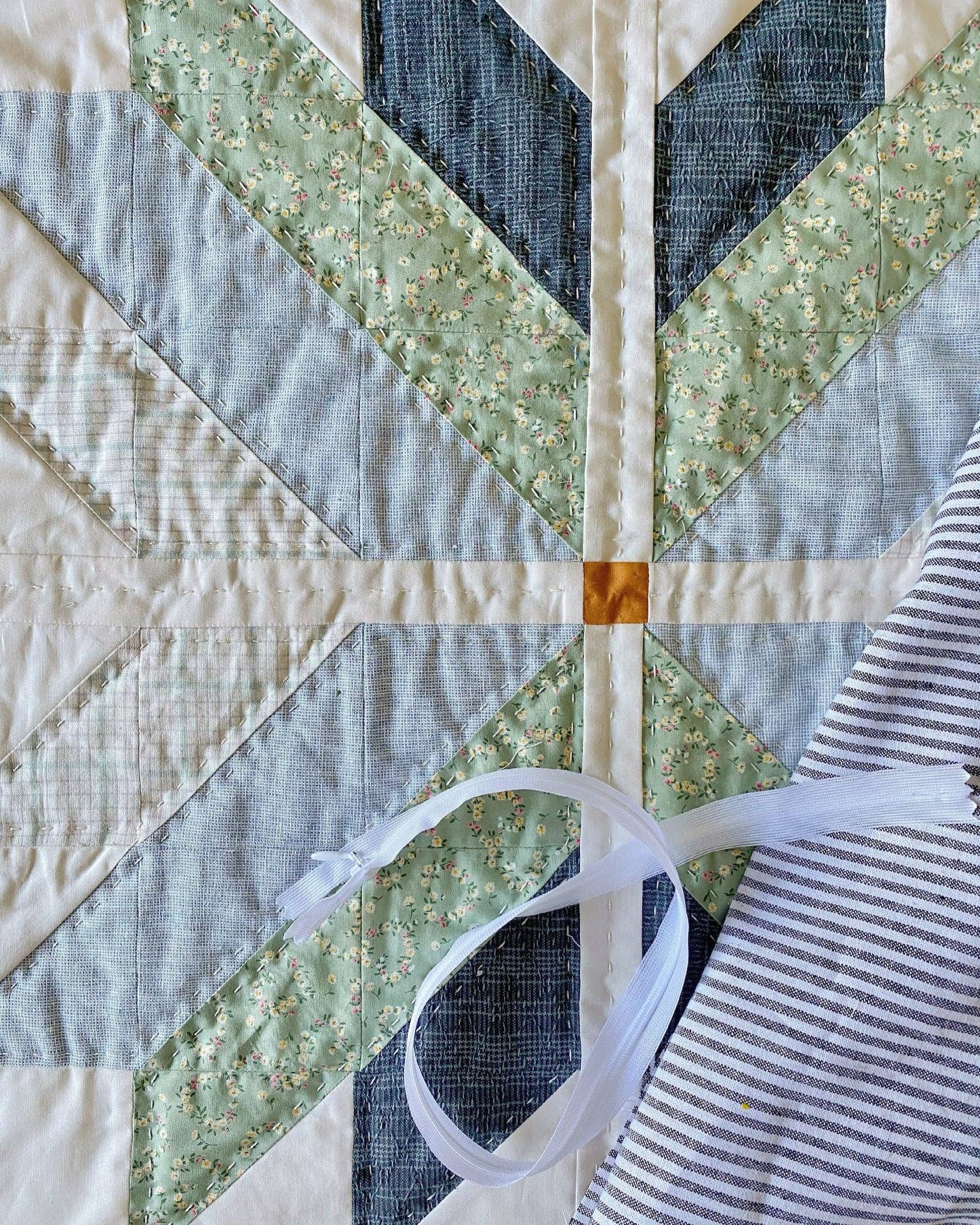 Quilt with geometric pattern featuring green, blue, and white fabrics.