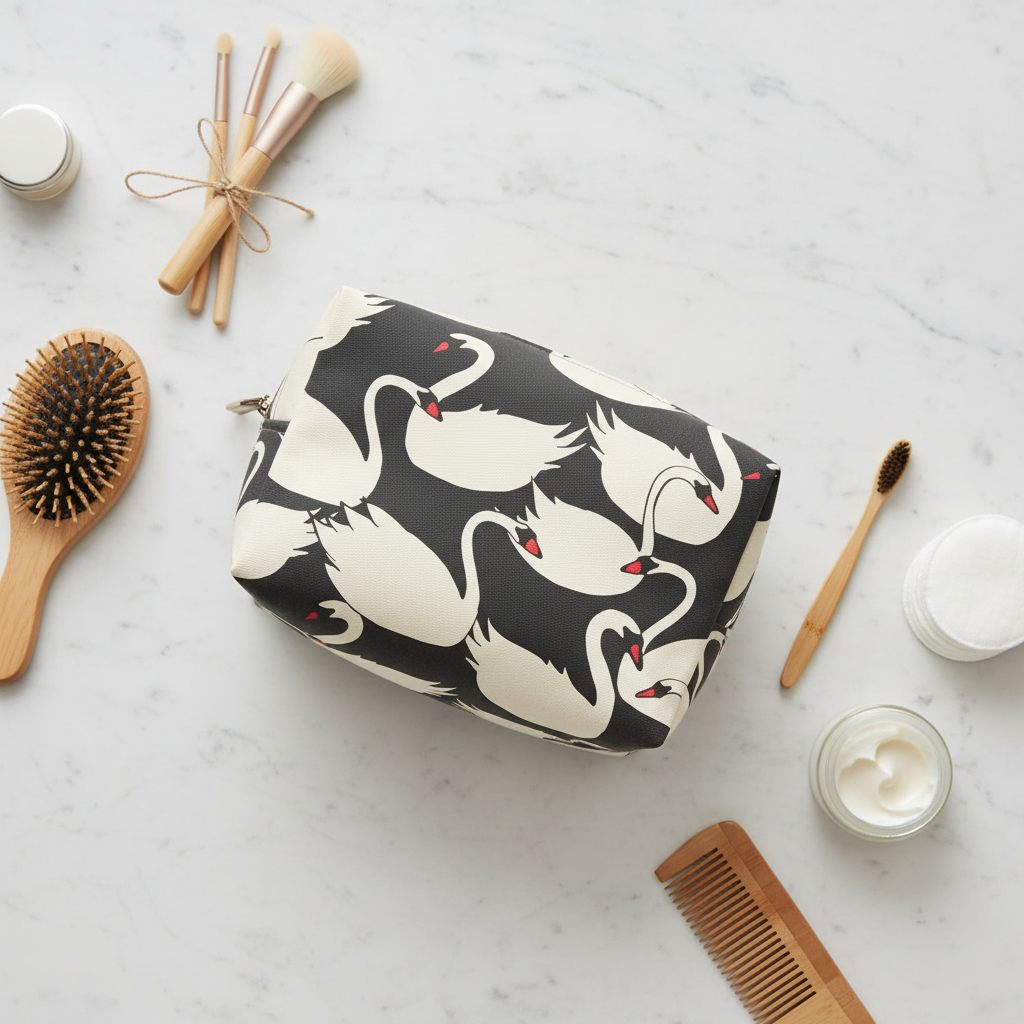 Cosmetic bag with swan pattern on a marble surface with beauty items.