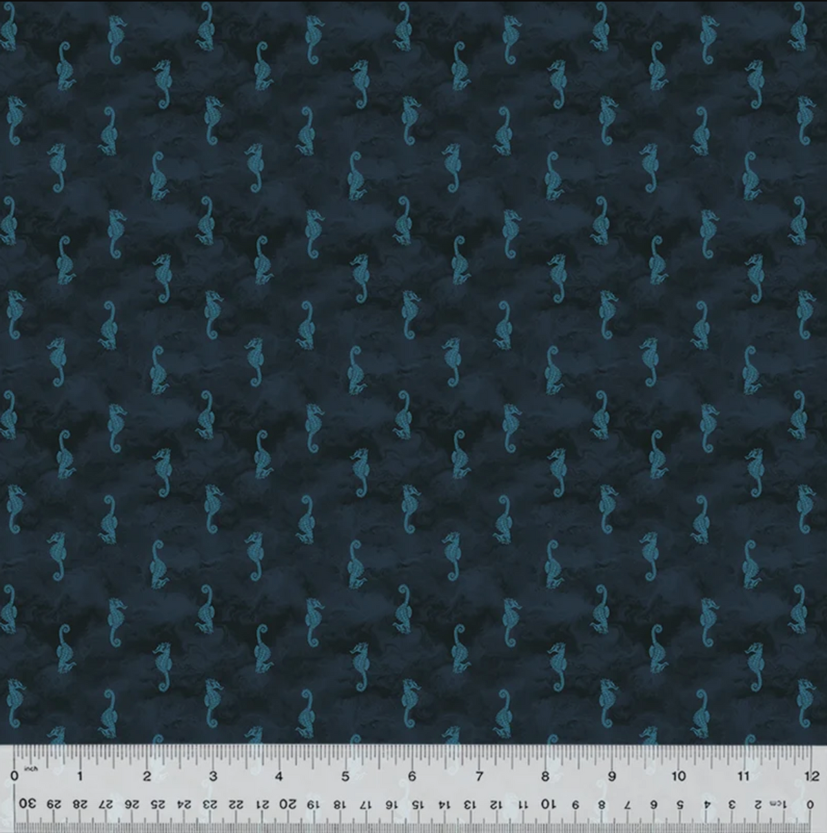 Dark navy blue fabric with a repeating pattern of small teal seahorses, shown flat with a white ruler along the bottom edge for scale.