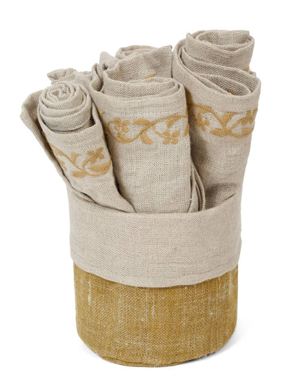 A set of rolled beige linen napkins with gold embroidered scrollwork, displayed inside a matching beige and gold fabric holder on a white background.