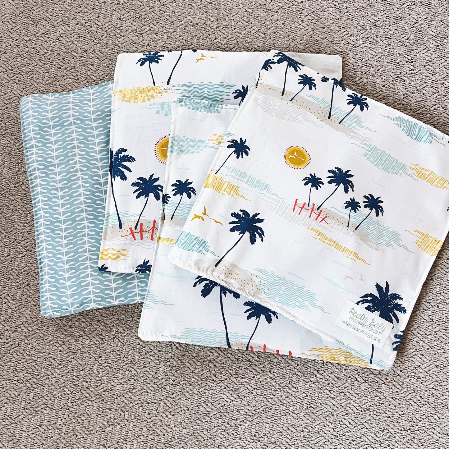 Set of four fabric swatches with palm tree and beach design on a textured surface