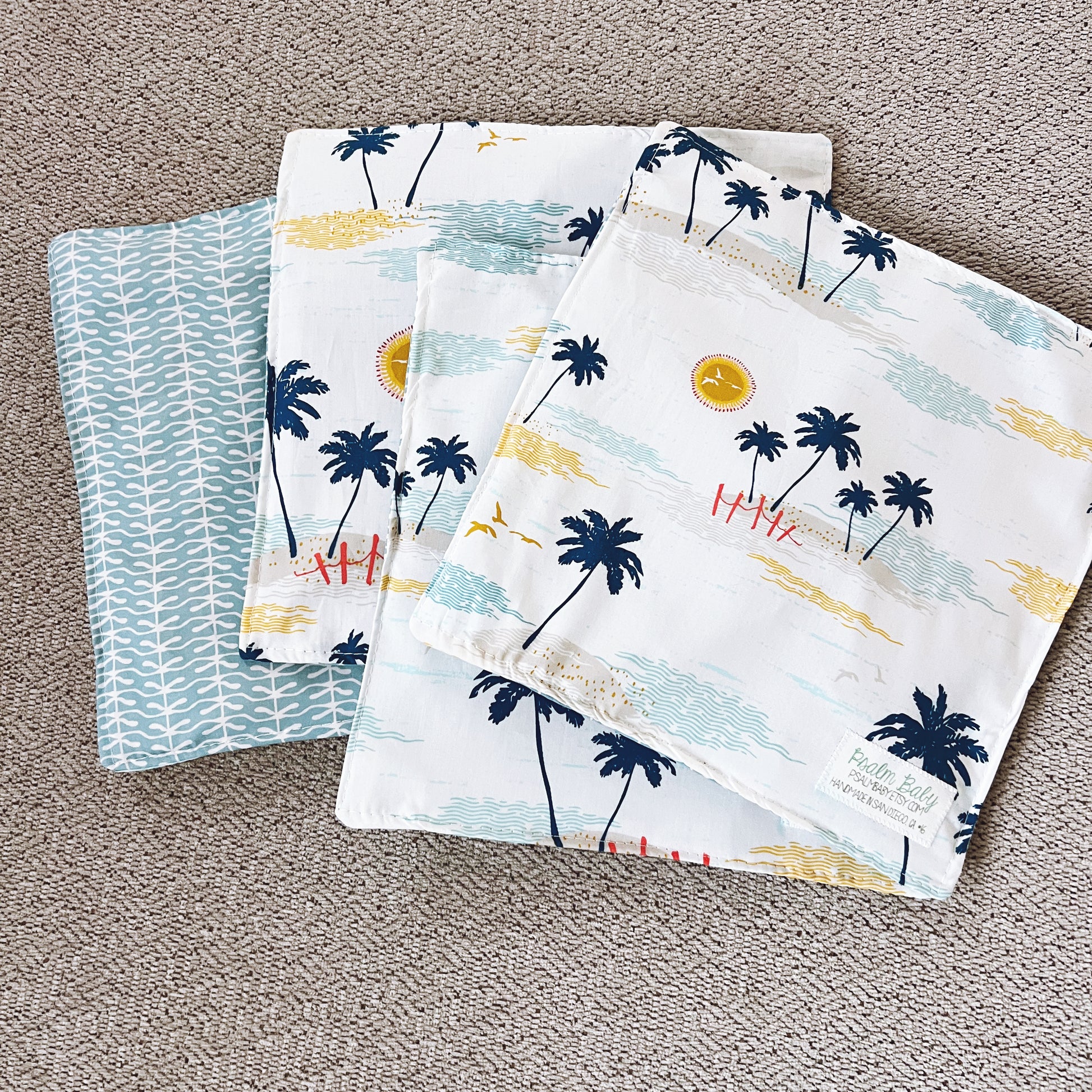 Set of four fabric swatches with palm tree and beach design on a textured surface