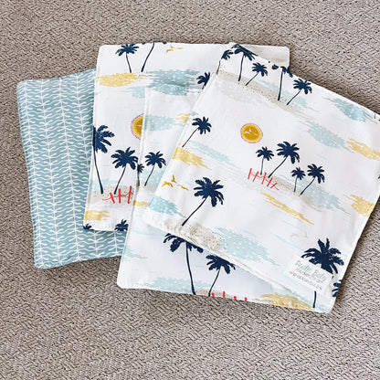 Set of four fabric swatches with palm tree and beach design on a textured surface